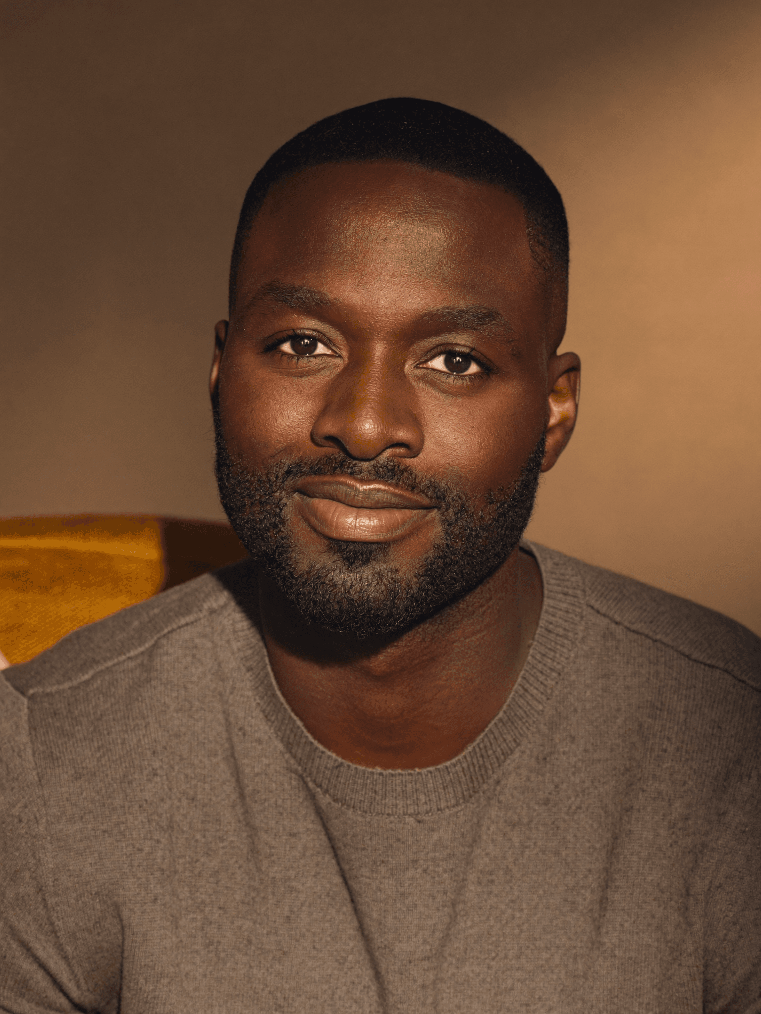 Portrait of a Black man with a beard and buzz cut wearing a grey sweater.